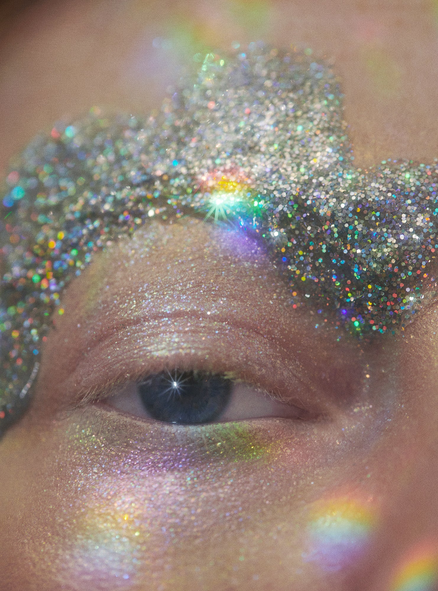 close-up of woman with cloud shaped metallic iridescent glitter brow eyeshadow makeup prismatic rainbow effect