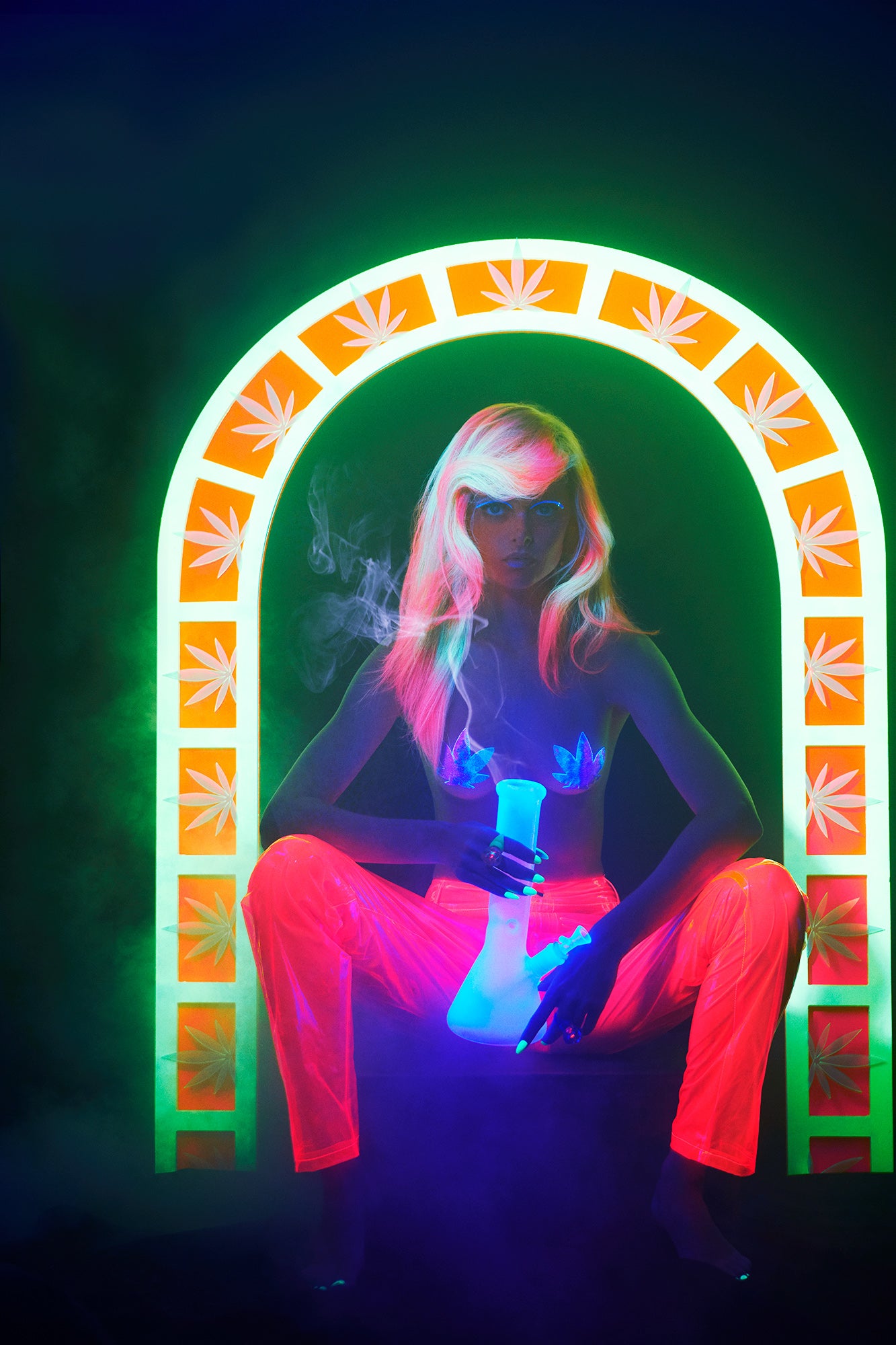 Glow-in-the-dark blacklight fashion editorial of woman sitting with neon hair smoking a weed bong