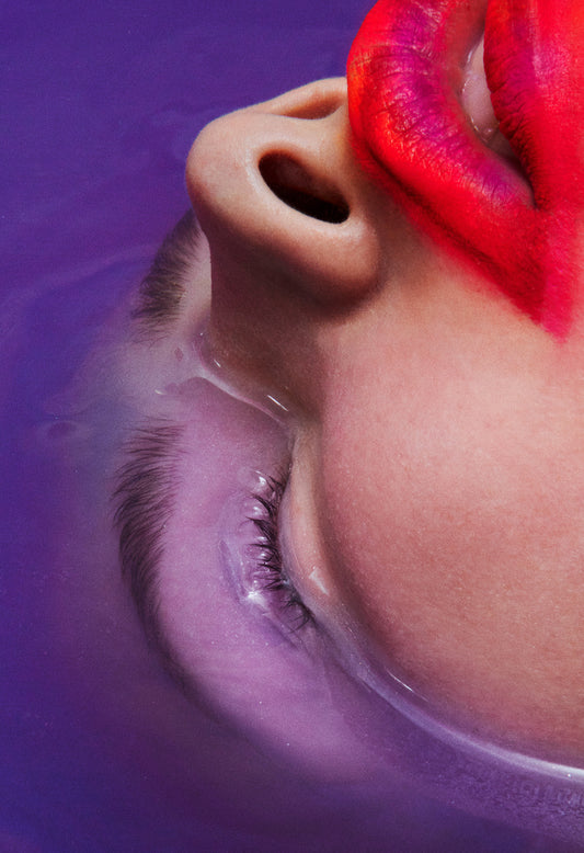 woman with red lipstain lipstick and waterproof makeup with head dunked underwater purple water bath bomb