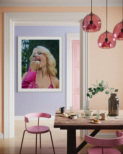 Framed artwork of a woman wearing blue eyeshadow and pink bikini. Amy Taylor of the band Amyl and the Sniffers, eats a messy ice cream cone that is dripping all over her face.