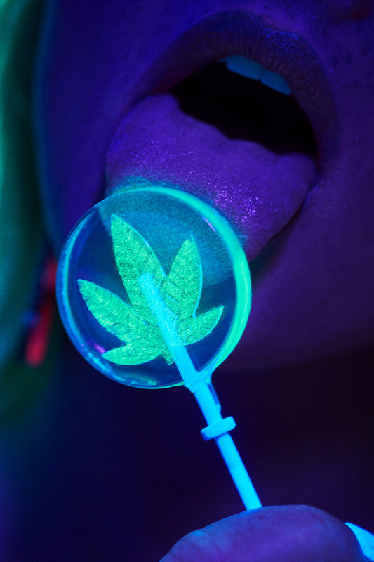 This image features an eye-catching art print titled "Potlick," which is a vibrant representation of a woman licking a lollipop with a prominent pot leaf design. The art print, available in various sizes, is a part of a limited edition series and comes unframed.