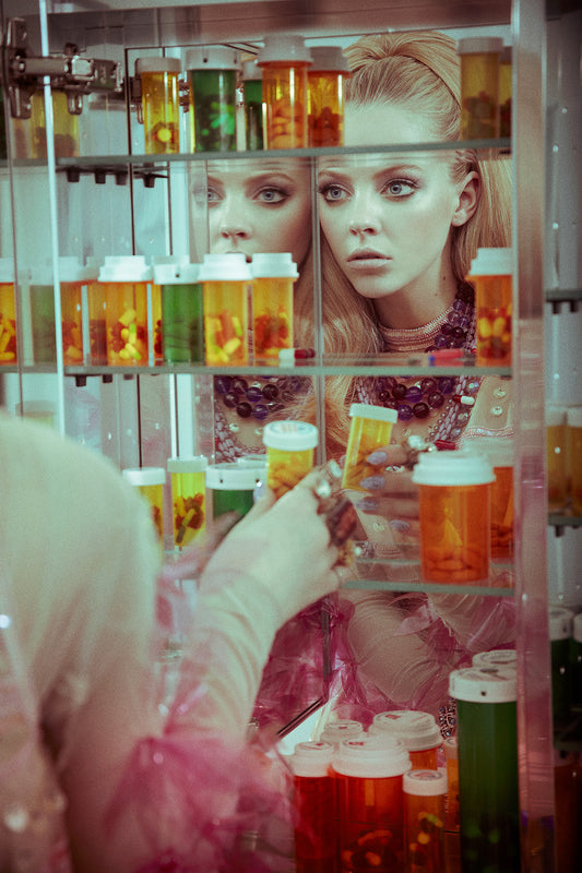 A limited edition fine art print featuring a woman looking into a medicine cabinet, with colorful pills and bottles visible.