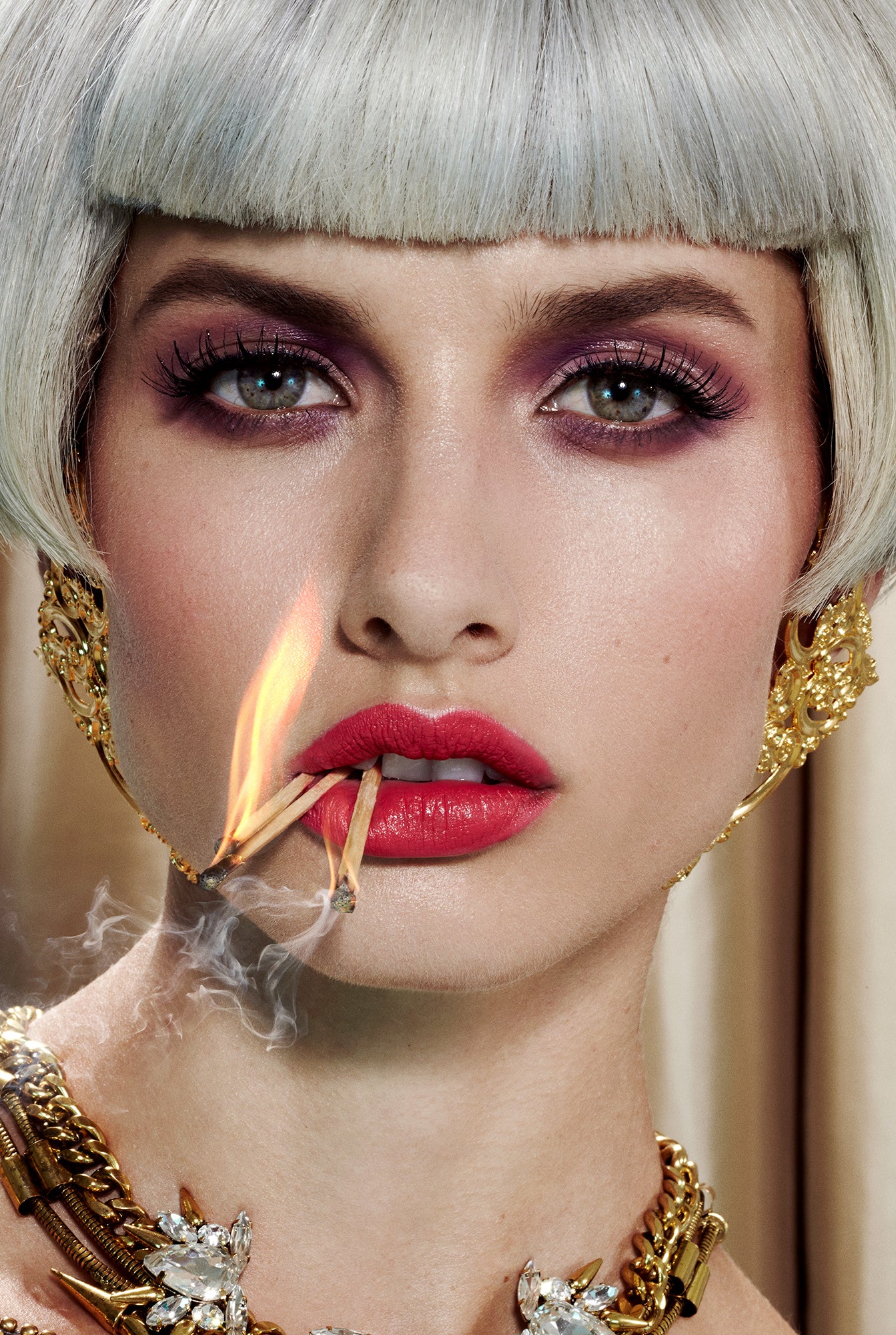 female model girl with fancy fine jewelry grey wig bob hair and matchsticks in her lips flame fire smoke